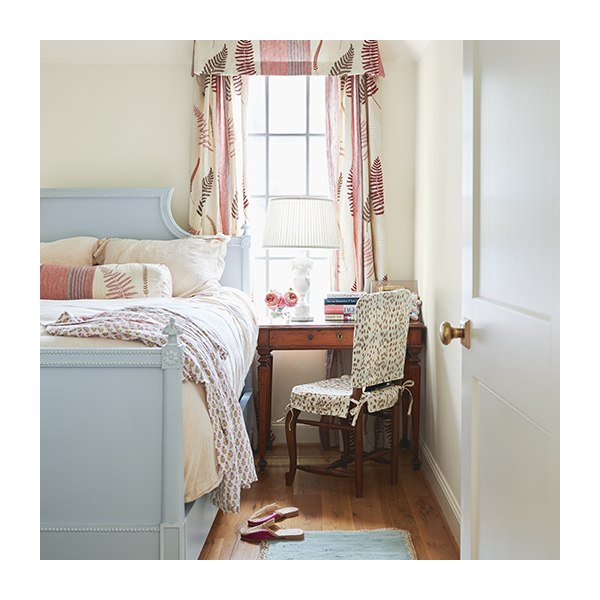 A French country bedroom with white-painted walls and door, a blue-painted ceiling and bedframe, patterned curtains, and wood floor.