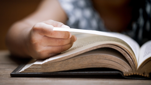 Close up view of person turning the page of a hardcover book.