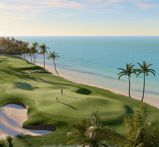 Two people golf on a coastal golf green with sand bunker and surrounding turquoise water.