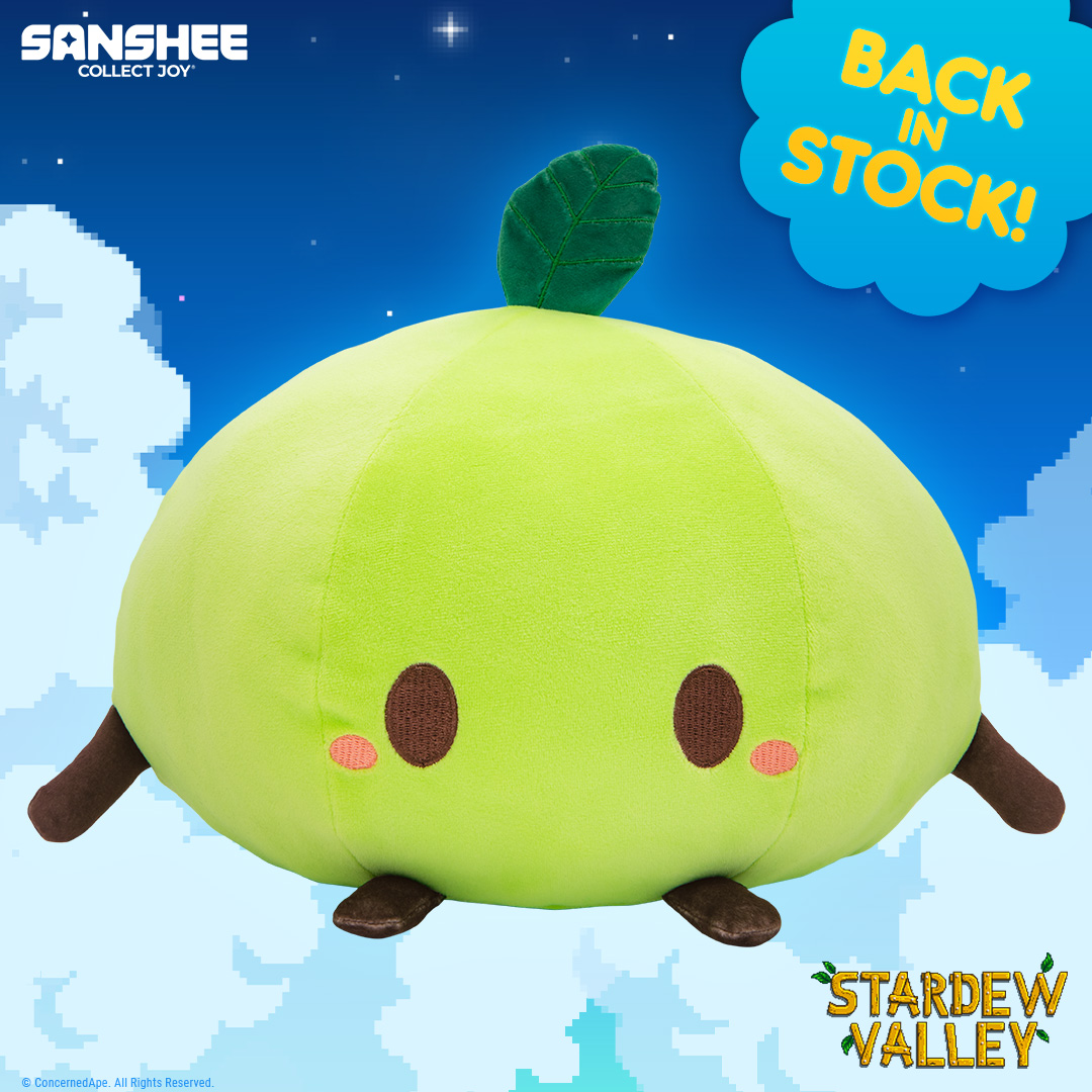 A green junimo plush in front of a blue cloudy background