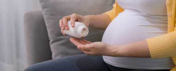 A pregnant woman holding a pill bottle. 