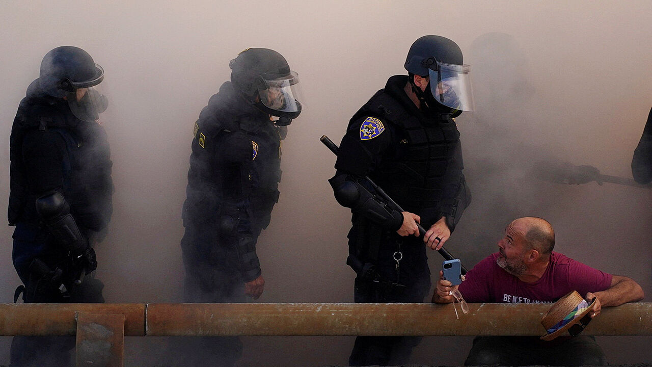 Police officers look at a demonstrator during a protest in Los Angeles against federal immigration raids in the city