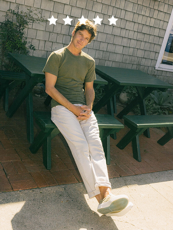 Male sitting on a bench, wearing slip on sneakers
