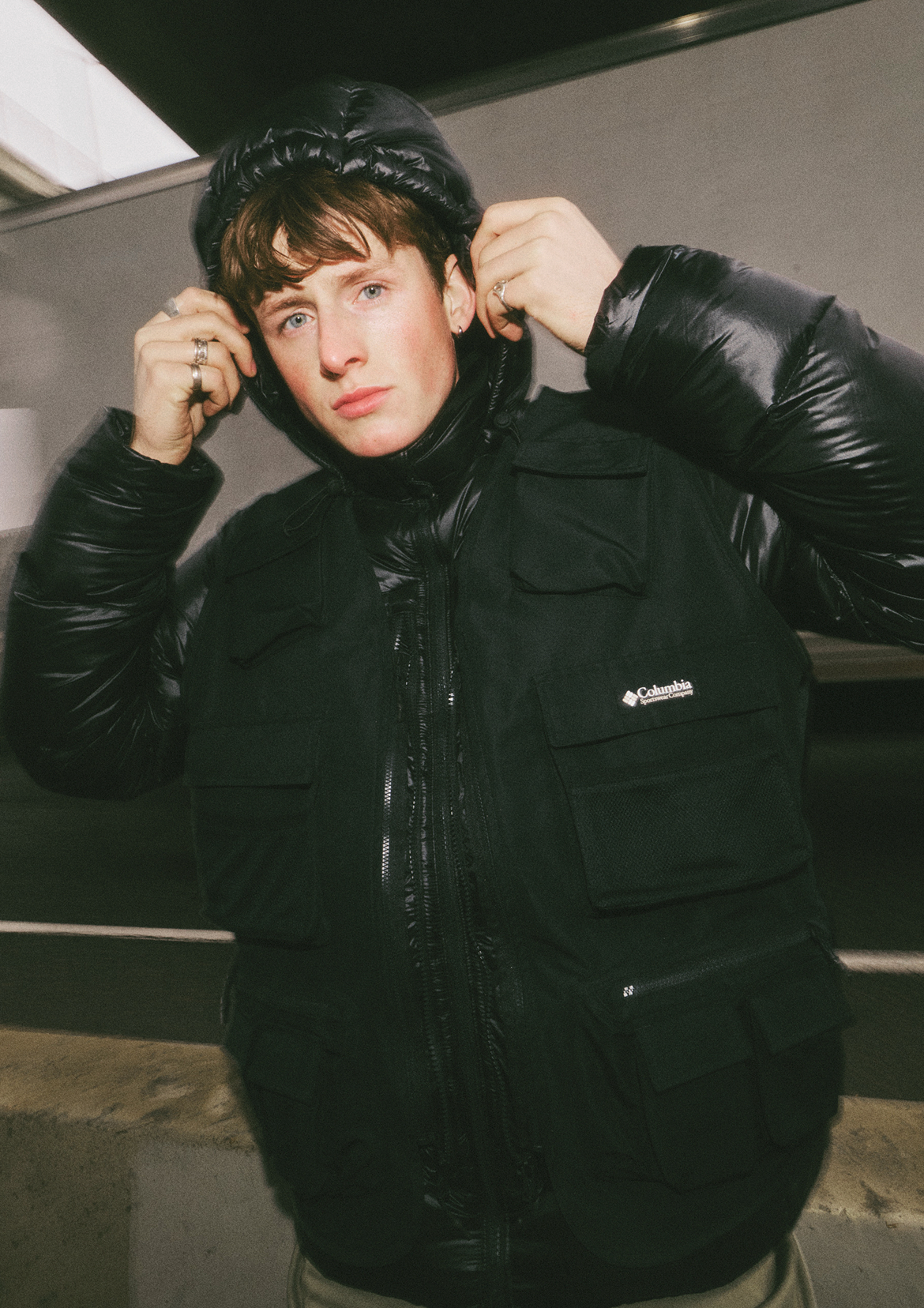 Close up of man in Dually Mountain Printed Outerchange Jacket in black pulling his hood up in an urban setting.