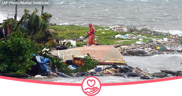 A man walks along a coastline filled with debris as a storm approaches. 