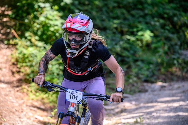 An enduro rider pedalling out of the saddle while taking part in an event.