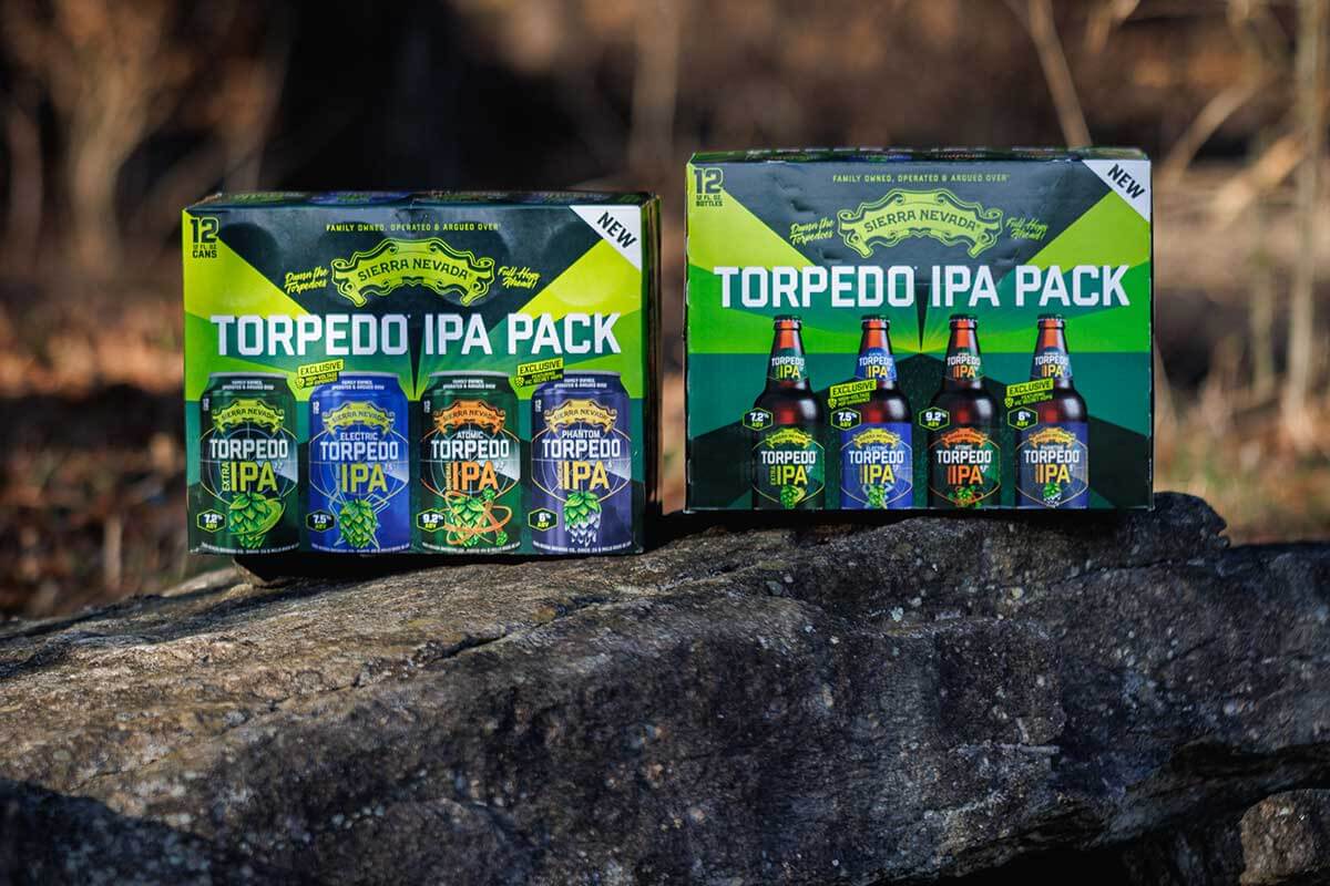Two Torpedo IPA Packs—one of cans, one of bottles—on top of a boulder