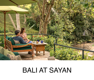A couple sit out on a terrace overlooking lush greenery. Text reads: Bali at Sayan.