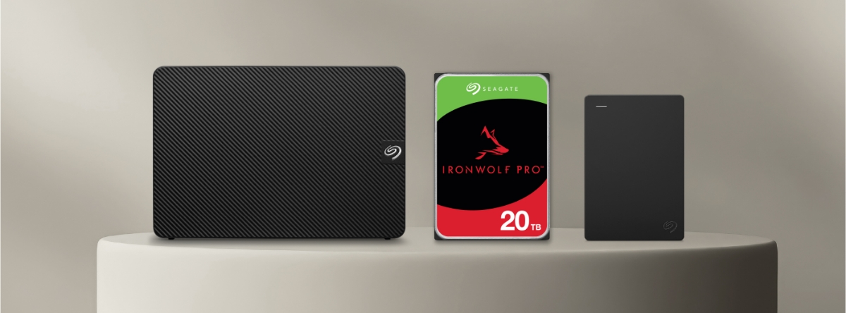 Image featuring a Seagate Expansion Desktop, IronWolf Pro NAS Hard Drive and Seagate Portable Drive on a plinth with a grey background.