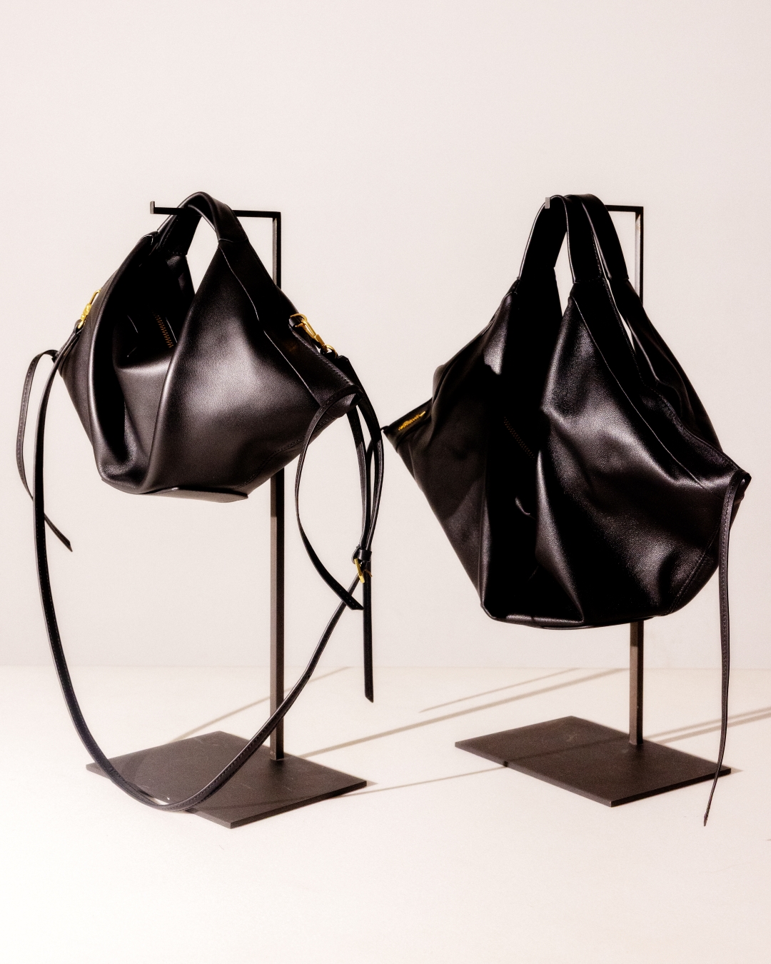an image of two black bags on a stand on a white surface