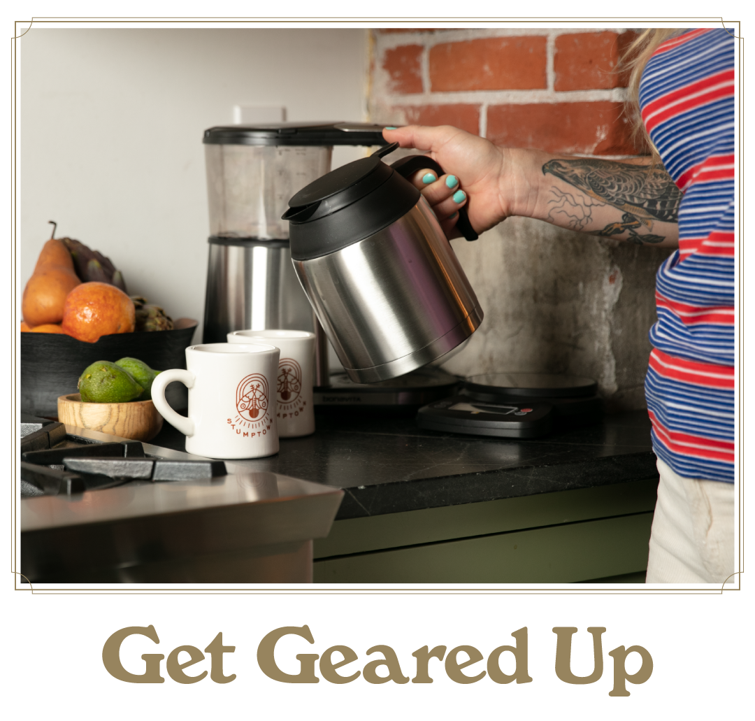 Stainless steel coffee carafe held next to a home brewer with mugs on the counter. Text reads “Get Geared Up.”