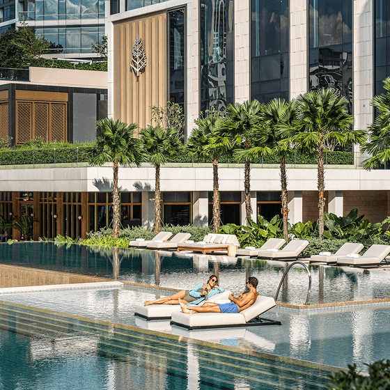 A couple lounging poolside in swimwear.