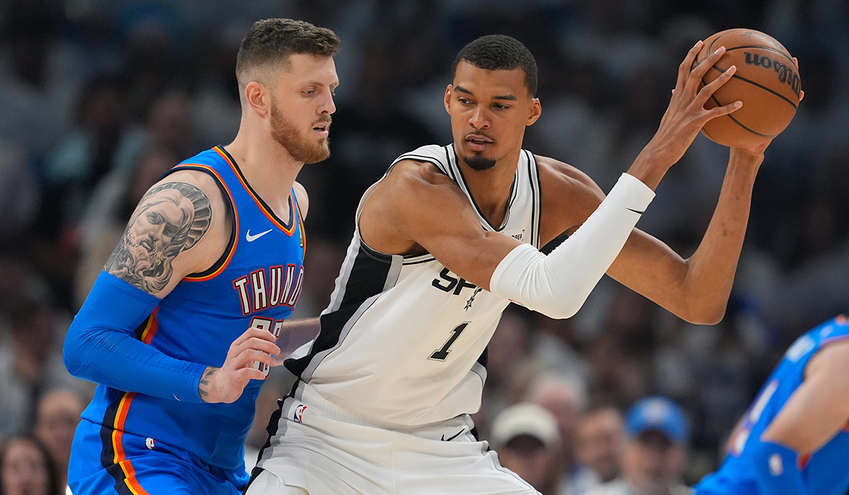 A Thunder player guards a Spurs player who has the basketball.