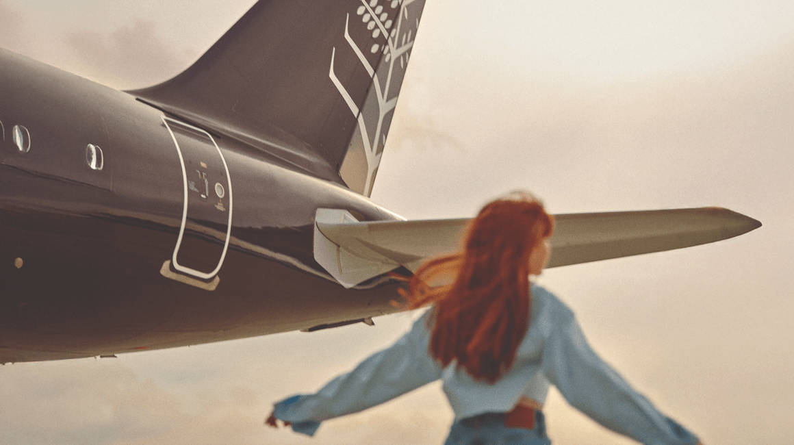 A woman standing beside an airplane.