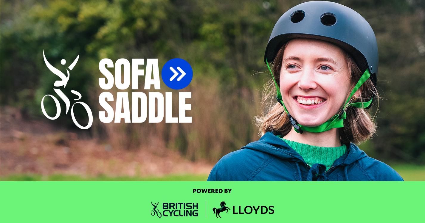 A rider smiles while looking to the side. She wears a skater-style helmet and casual clothing and there is a blurred parkland background.