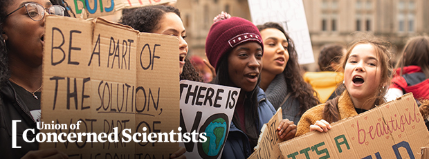 Group of young activists holding signs at a climate protest.