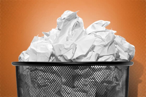 A trash can overflowing with crumpled-up papers on an orange background.