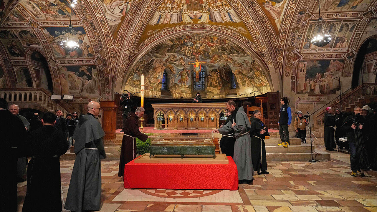 Friars pray before the remains of Francis of Assisi inside the Basilica of St. Francis of Assisi in Assisi, Italy