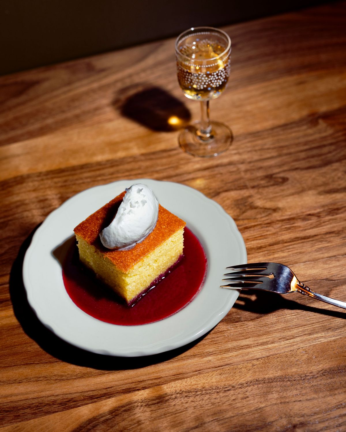 A square of olive-oil cake on a plate with a fork.