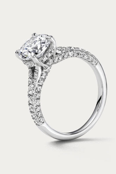 A white metal ring with a round cut center stone and diamonds along the shank.