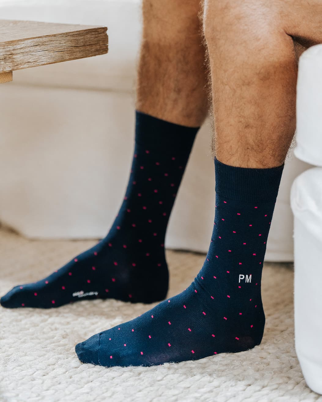Close up of man wearing blue dress sock with letters "PM" monogrammed on. 