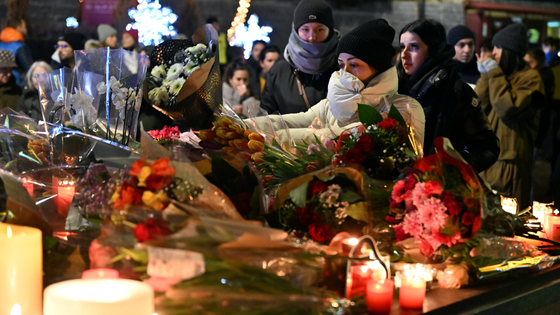 Mourners leave flowers and candles.