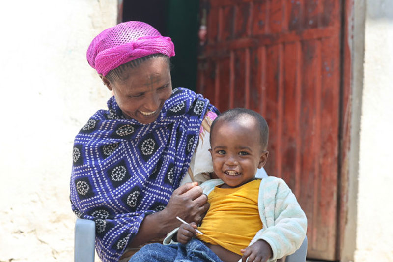 Mother sitting outside holding her child.