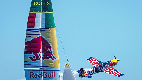 A Red Bull stunt aeroplane flies close to the Red Bull Italy SailGP Team F50 catamaran during a practice session ahead of the ORACLE Perth Sail Grand Prix in Perth, Australia