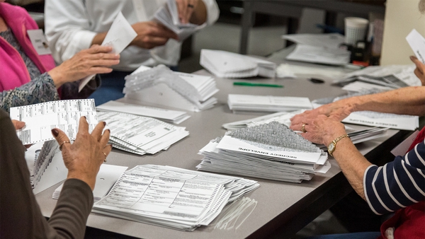 Several people count stacks of ballots at a table on election night