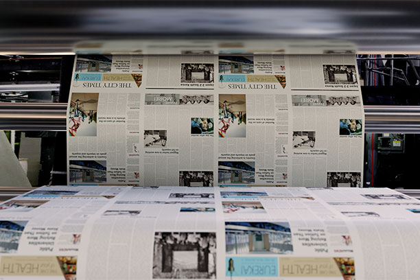 Newspapers rolling off a printer.