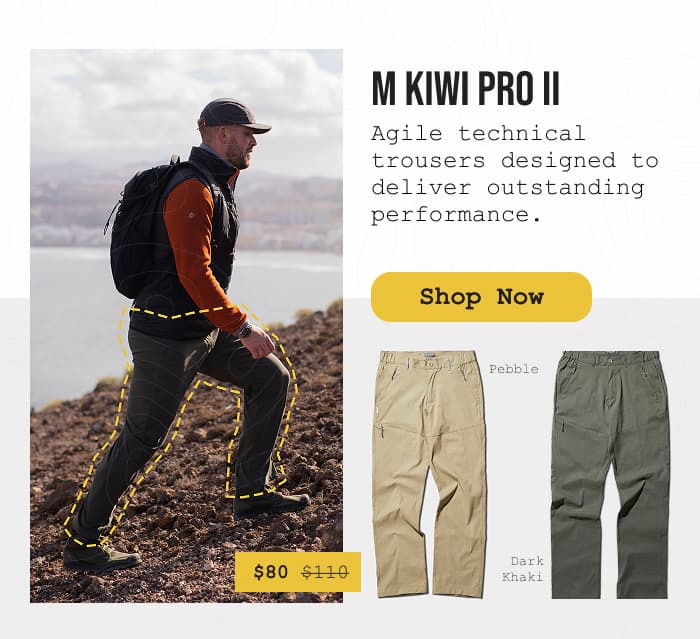 Photo of a man hiking up a hill in front of a moody lake while wearing Kiwi Pro II pants.