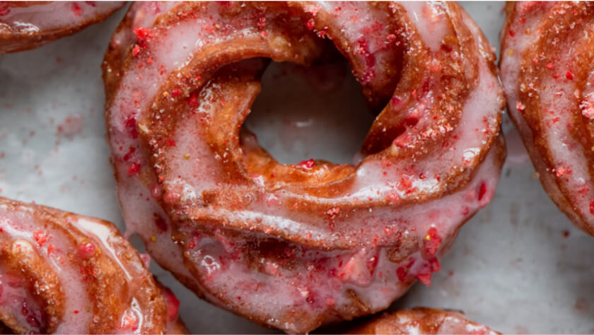 Zoomed-in image of strawberry red circular crullers.