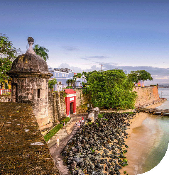 Historic stone guard tower by the ocean with a rainbow in the sky. San Juan, Puerto Rico.