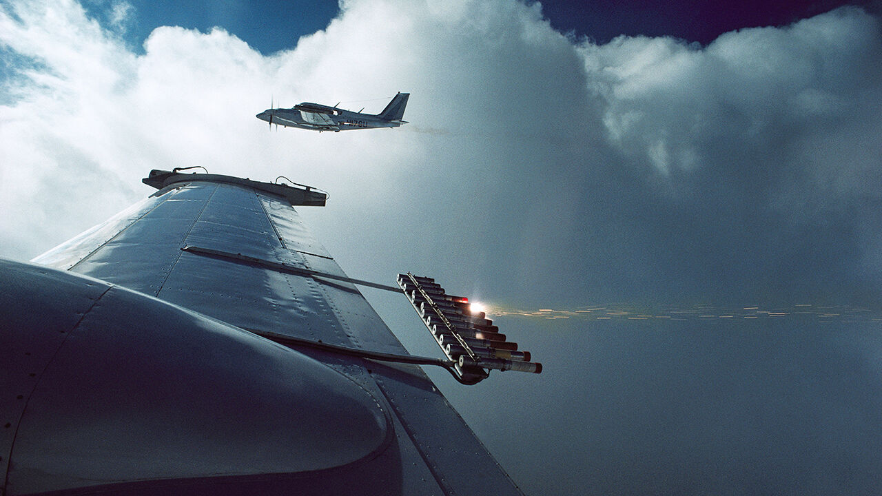 Cloud seeding equipment on the wing of plane, viewed through window, flying over North Dakota.