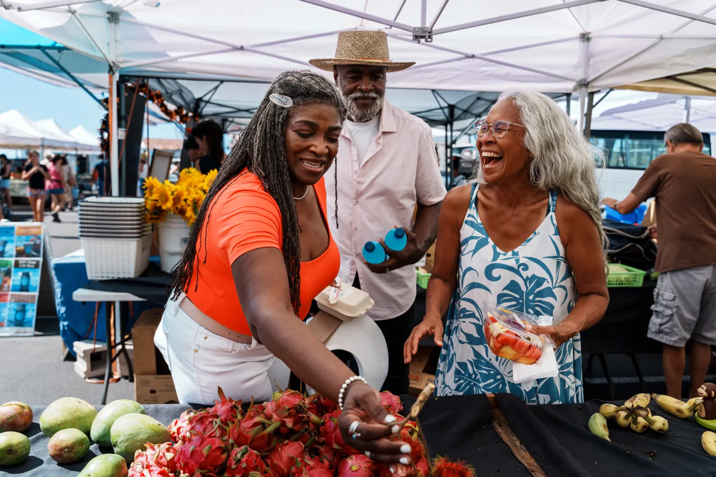 Three people looking at fruit in a market