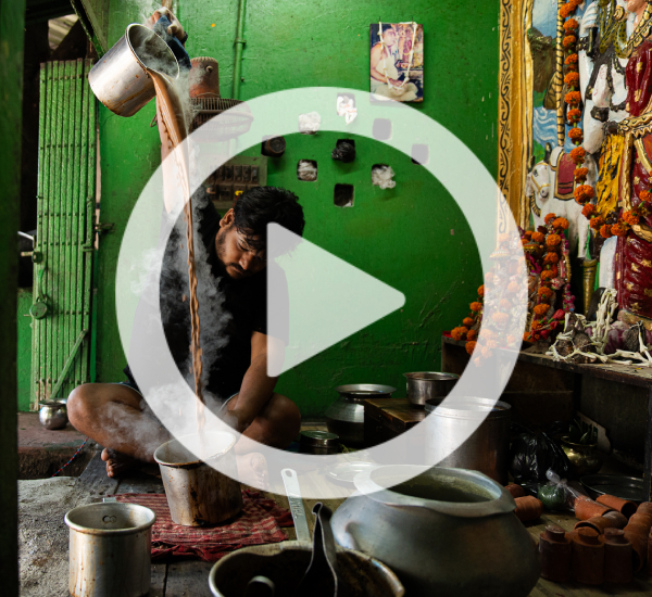 Person making chai tea in room with pots and pans on the floor.