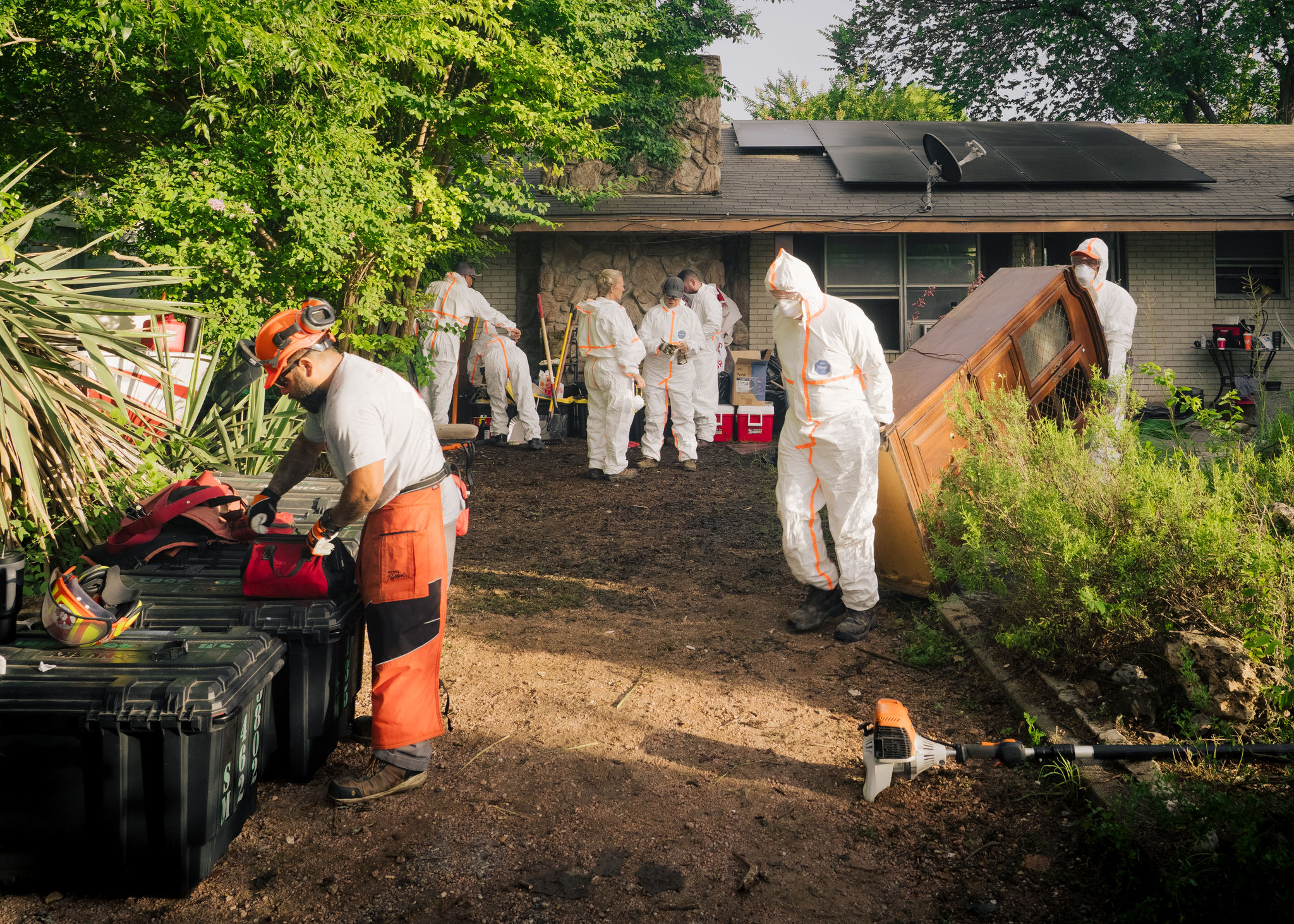Team Rubicon Greyshirts in protective suits clearing debris outside a flood-damaged home in Texas.
