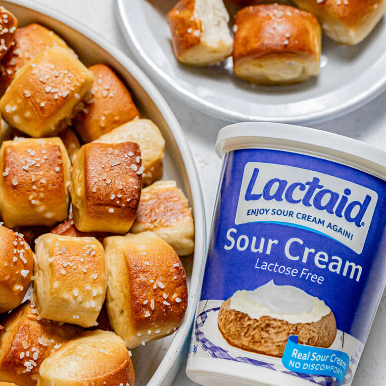 Close-up of soft pretzel bites with a thing of sour cream to the right.