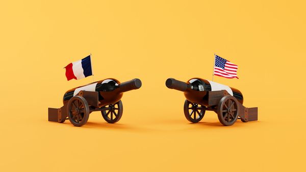 illustration of two wine-bottle cannons on wooden carts, one with a French flag and the other with an American flag, facing each other on a yellow background.
