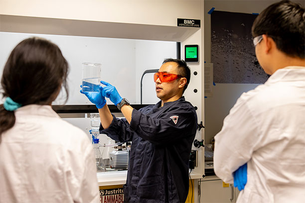  Environmental researcher Derek Ho displays a beaker of liquid for onlookers in the lab.