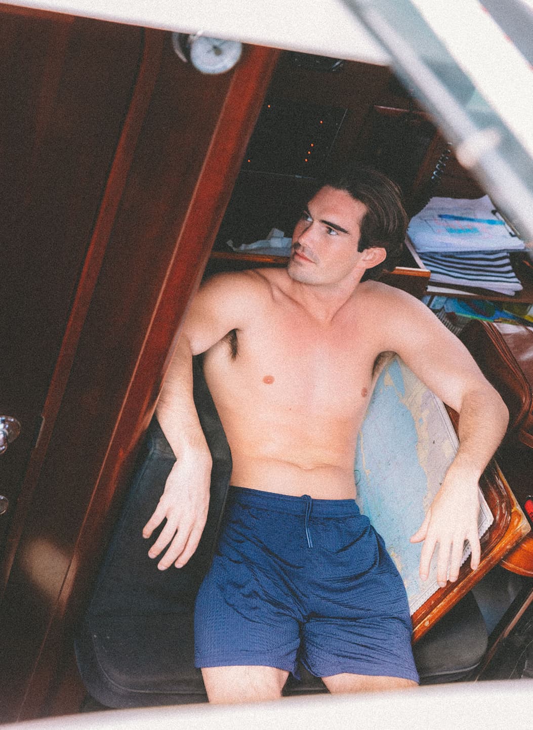 Shirtless man sitting on boat wearing navy blue lounge shorts