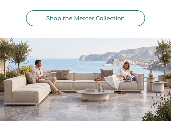 A couple relaxes on a spacious, modular outdoor sectional sofa with light cushions on an open terrace overlooking a scenic coastal bay. Image Text: Shop the Mercer Collection