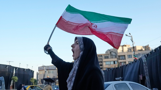 A woman holds an Iranian flag.