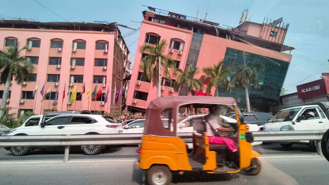 Motorists ride past a bright pink damaged building after a strong earthquake struck central Myanmar, in Mandalay, Myanmar.