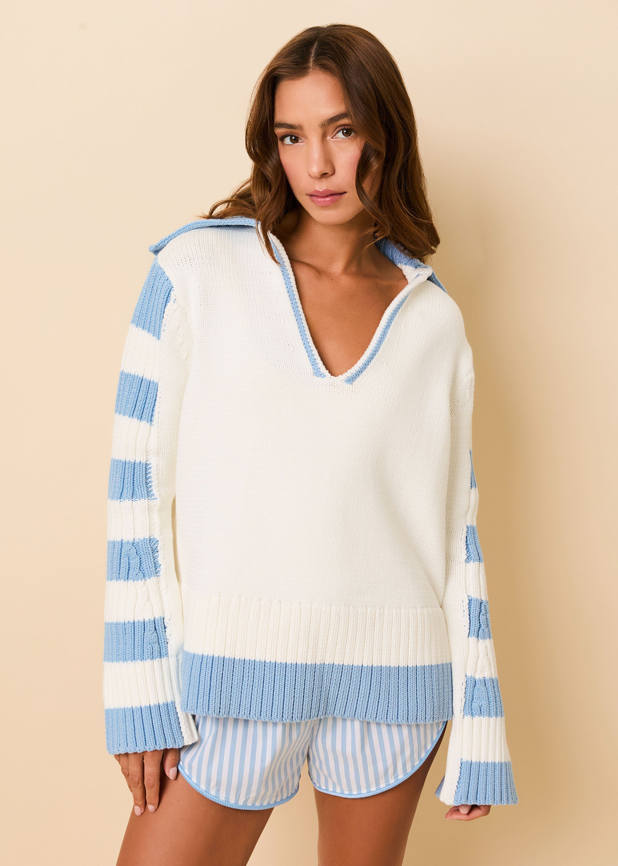 woman in a white sweater with blue stripe detailing on the arms and collar