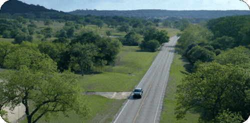 F-150 Lightning driving on a freeway surrounded by lush fields.