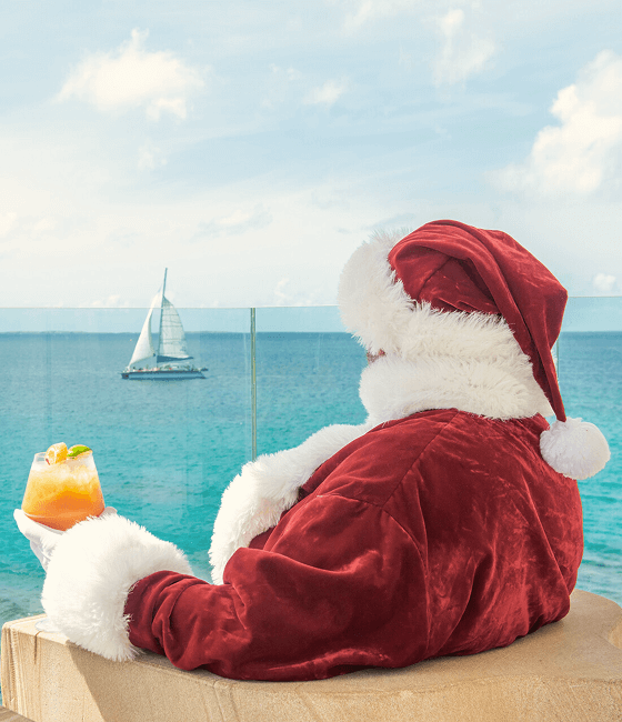 Santa relaxing with a cocktail as he marvels at the ocean.