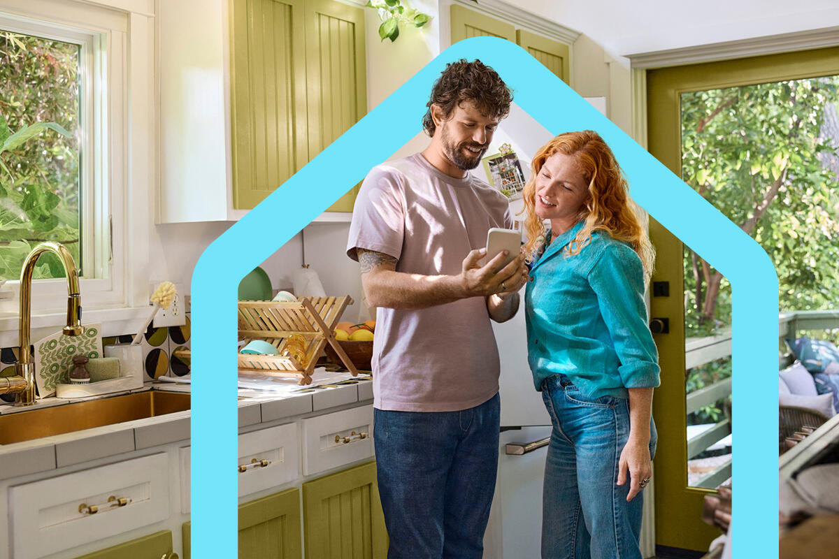 Couple in their kitchen looking at a mobile phone