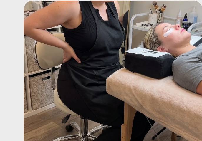Artist hunched over a client on a flat massage table, demonstrating poor ergonomics.