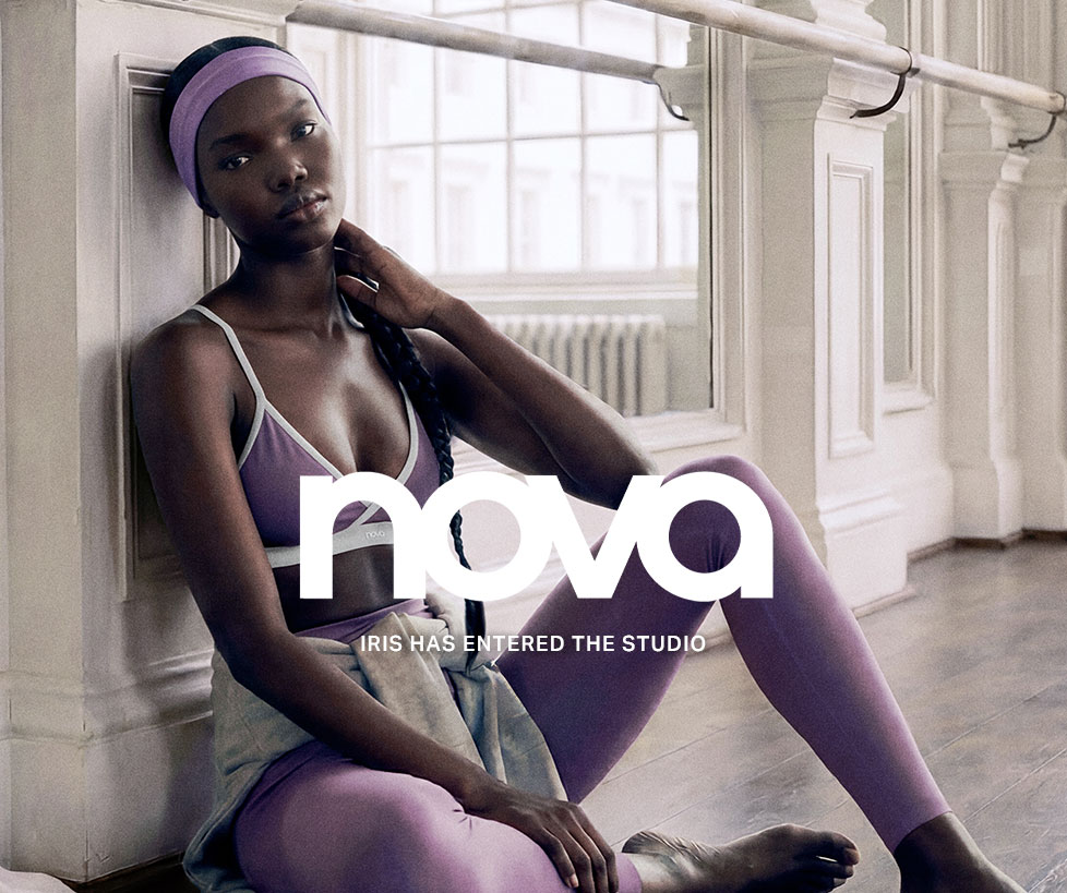Iris, a woman in Nova purple sports bra, leggings, and headband, sits relaxed in a bright studio, promoting comfortable activewear.